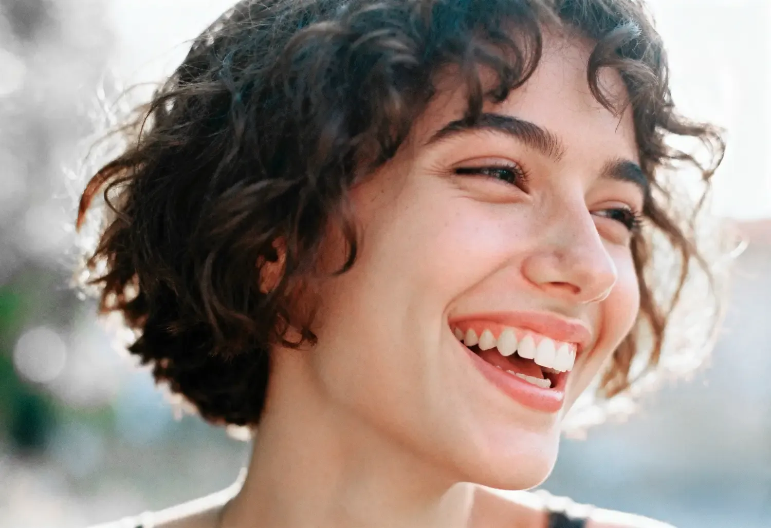 Mujer sonriendo con dientes saludables, cepillo dental y fondo blanco luminoso.